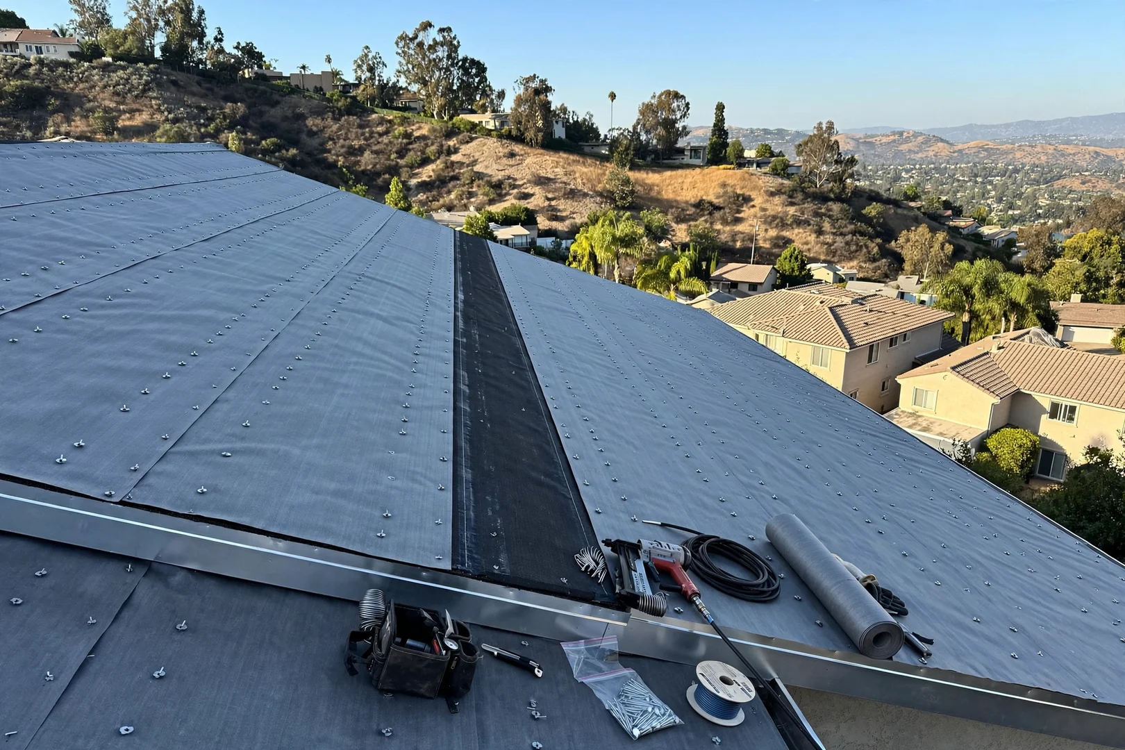 Synthetic underlayment rolled and fastened across a steep hillside roof slope